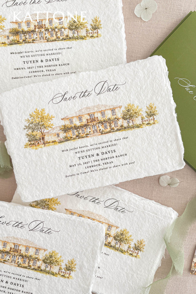 Angled overhead close-up of handmade paper save the date card with deckled edges, elegant black calligraphy, custom watercolor estate illustration, warm yellow and green landscape details, olive green stationery, and soft sage ribbon styling
