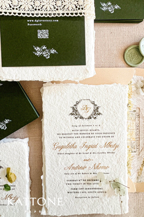 An elegant flat-lay of a vintage-style wedding invitation suite from Attone Paper. The set includes a central cream-colored textured paper invitation card with gold and black script text, a dark green envelope with white lace trim, a wax seal, and other coordinating stationery pieces on a neutral beige background.
