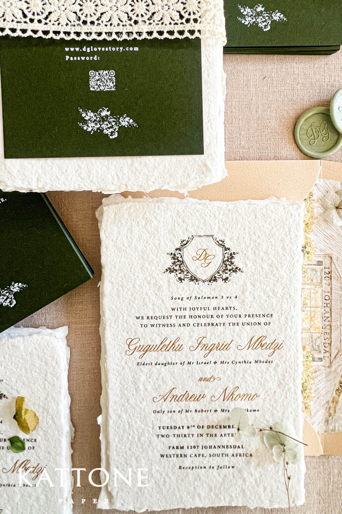 An elegant flat-lay of a vintage-style wedding invitation suite from Attone Paper. The set includes a central cream-colored textured paper invitation card with gold and black script text, a dark green envelope with white lace trim, a wax seal, and other coordinating stationery pieces on a neutral beige background.