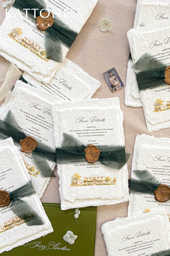 A styled flat-lay of wedding invitation suites featuring textured off-white paper cards with dark green watercolor ribbons, bronze wax seals, and gold botanical illustrations, arranged on a beige linen background.