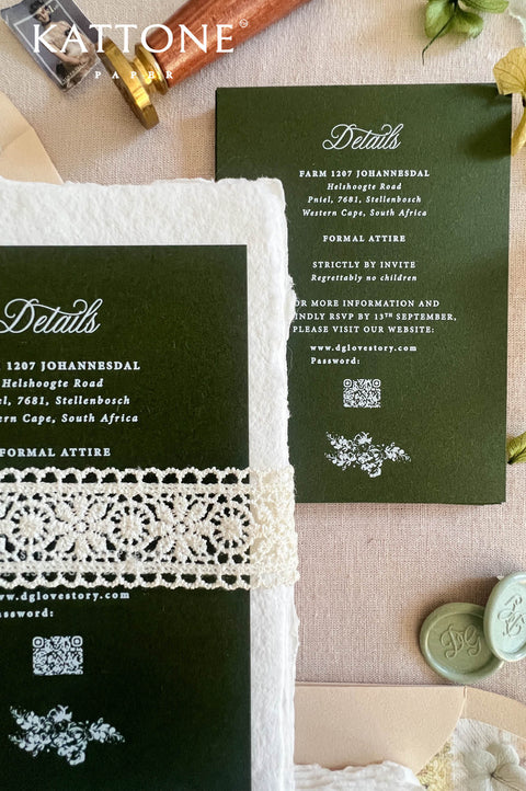 Dark green wedding invitation suite with white lace trim, displayed on a beige fabric background with wax seals, a gold pen, and floral accents. The suite includes a main invitation card, a details card, and a matching envelope.