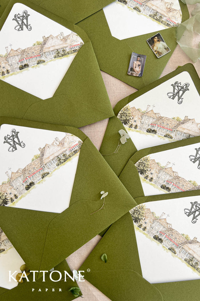 Top-down close-up of olive green wedding envelopes with custom watercolor country club venue liners, featuring an elegant estate building, red awnings, landscaped greenery, and black personalized monogram