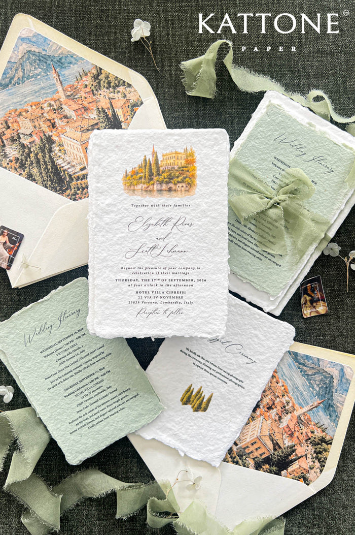 Top-down flat lay of luxury Lake Como wedding invitation suite featuring ivory handmade deckled-edge paper, watercolor lakeside villa artwork, sage green itinerary cards, soft green silk ribbon, ivory envelopes with Italian village and mountain watercolor liners, and elegant destination wedding stationery on a dark textured background