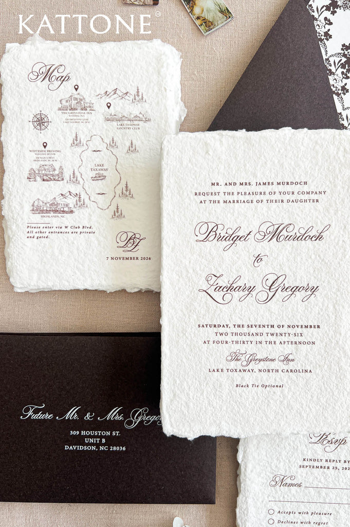 A styled flat-lay of wedding stationery from Kattone, featuring a cream-colored map invitation, a central wedding invitation card with elegant cursive text, a dark brown RSVP card, and a partial RSVP reply card on a neutral beige background.