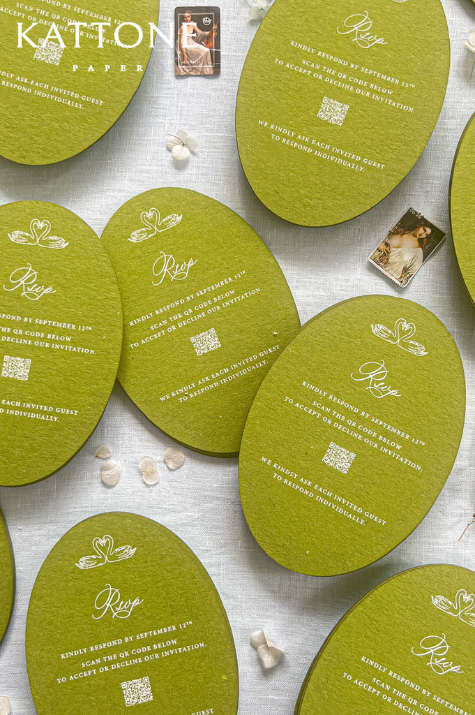 Oval lime green invitation cards with white printed text and decorative motifs, arranged on a light fabric background with small scattered shells and a Katton Paper logo in the top left.
