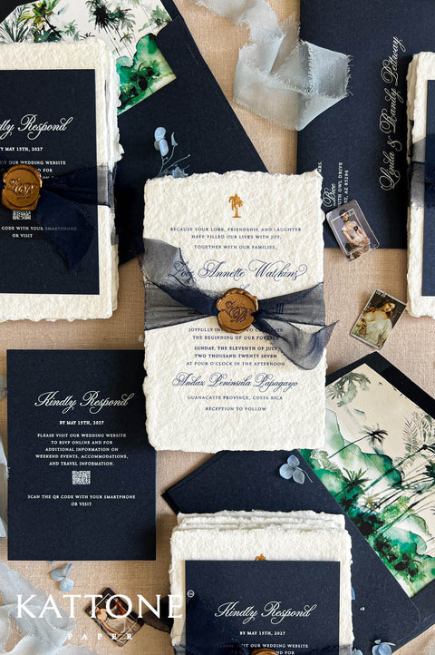 A styled flat-lay of wedding stationery from Kattonal, featuring navy blue and cream textured paper invitations, envelopes, a wax seal, botanical prints, and small photo cards arranged on a neutral background.