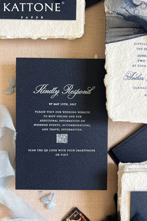 Top-down detail view of luxury navy and ivory wedding stationery featuring calligraphy-addressed dark navy envelope, handmade deckled-edge invitation, monogram wax seal, sheer navy ribbon, RSVP card, and elegant destination wedding styling