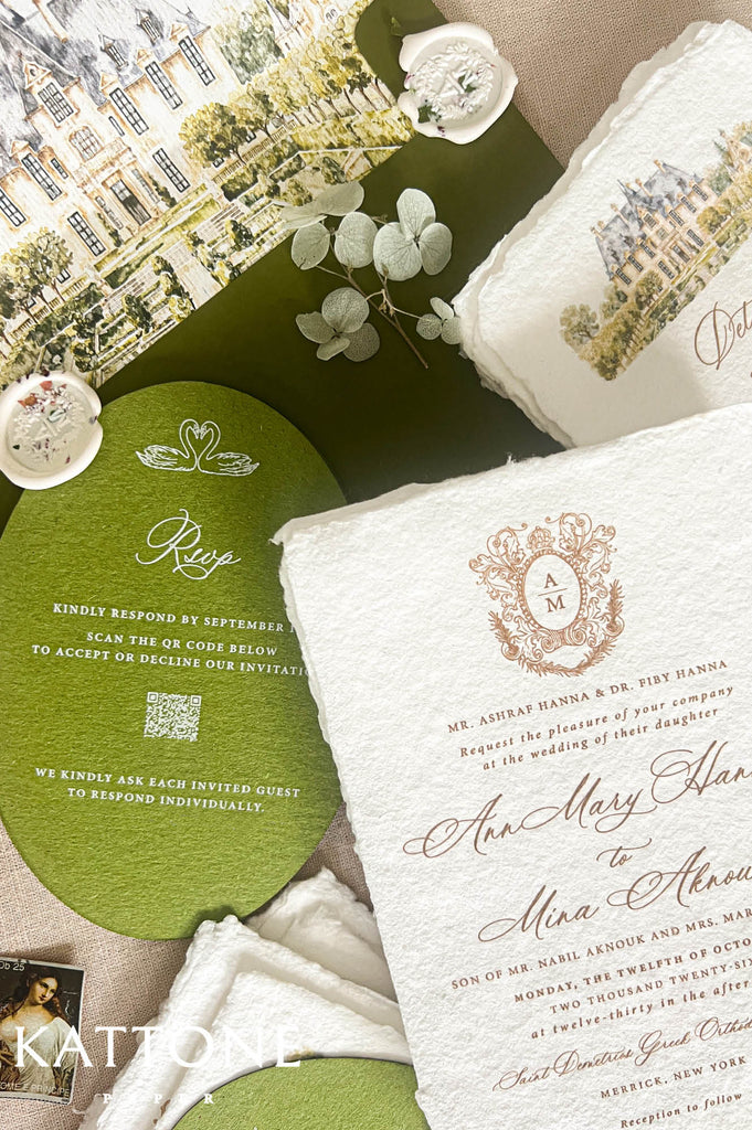 A styled flat-lay of wedding stationery and gift packaging, featuring a cream textured invitation card with gold script and crest, a round olive green RSVP card, a matching green envelope, a white gift box with a printed illustration, and small decorative ceramic dishes on a neutral fabric background.