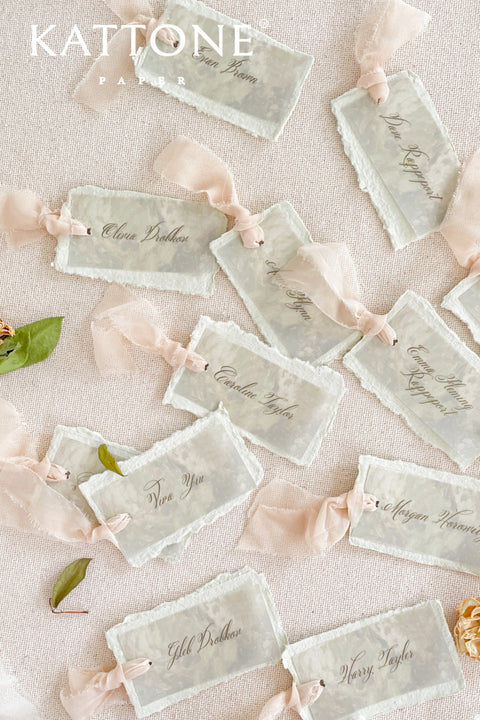 Add ethereal elegance to your event with our handmade paper place cards, crafted from delicate cotton rag paper and layered with a translucent vellum top sheet. Each card is finished with naturally torn deckled edges and soft blush ribbon, creating a dreamy fine-art look perfect for weddings, showers, and romantic celebrations. These unique layered cards bring texture, movement, and refined beauty to every tablescape.