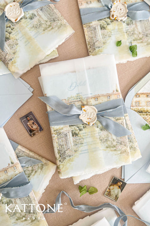 A styled flat-lay of Kattone wedding stationery featuring vintage-inspired printed cards, envelopes, ribbons, and wax seals on a neutral kraft paper background.
