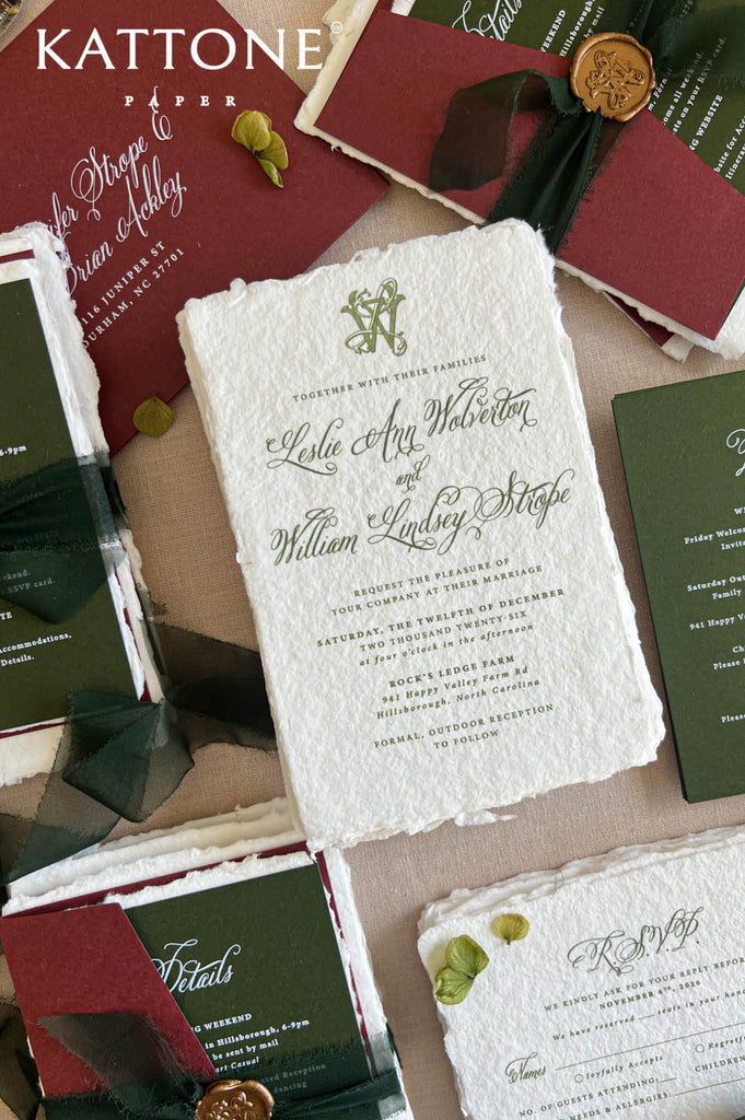 A styled flat-lay of vintage-inspired wedding stationery from Kattone Paper, featuring a central off-white textured paper invitation with green script, surrounded by matching dark green and burgundy envelopes, cards, and wax seals on a neutral background.