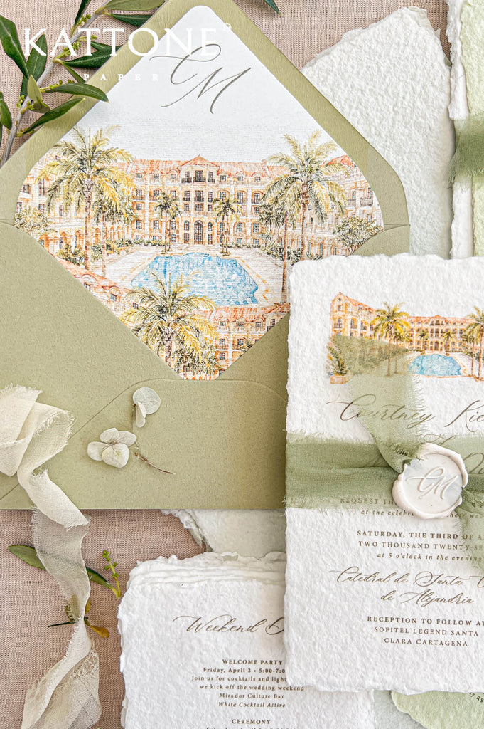 Close-up overhead view of handmade deckled-edge wedding invitation with watercolor tropical resort artwork, sage green silk ribbon, ivory monogram wax seal, and coordinating pale green weekend details card on neutral linen