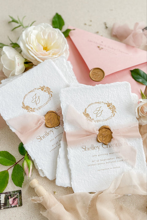 Announce your wedding with elegance and artistry through our handmade paper Save the Date cards, featuring a gold monogram wreath, soft blush silk ribbon, and hand-stamped wax seal. Each card is crafted on luxury 100% cotton handmade paper with deckled edges, offering a tactile and romantic texture that perfectly captures fine-art wedding style.