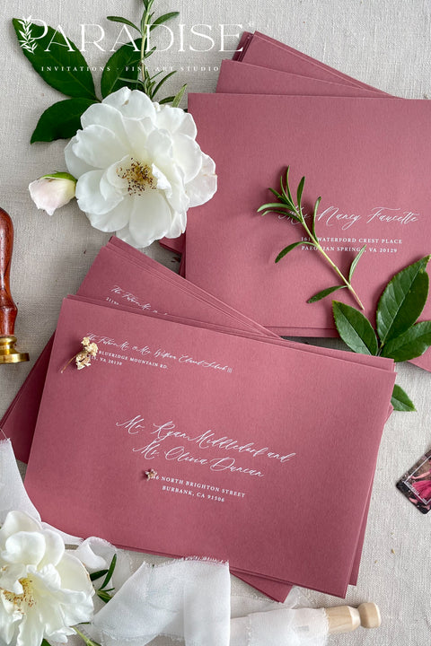 Wedding envelopes with white ink address printing, crafted from premium paper in a muted romantic tone and styled to highlight crisp lettering and refined stationery quality.