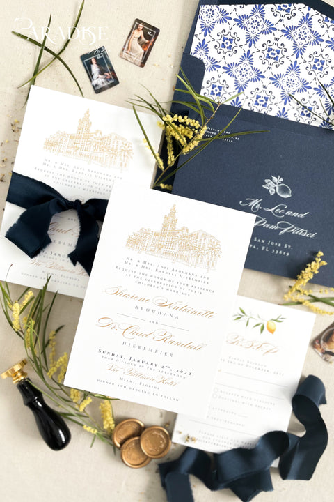 Inspired by the golden light and charm of European summers, this wedding invitation suite combines custom hand-drawn architecture with delicate watercolor lemons for a design that’s both luxurious and full of life. The venue illustration is created by hand, transforming your wedding location into a piece of art that sets the tone for your day. Paired with rich navy envelopes, an ornate blue patterned liner, and velvet ribbon accents, the result is a suite that exudes elegance and personality.