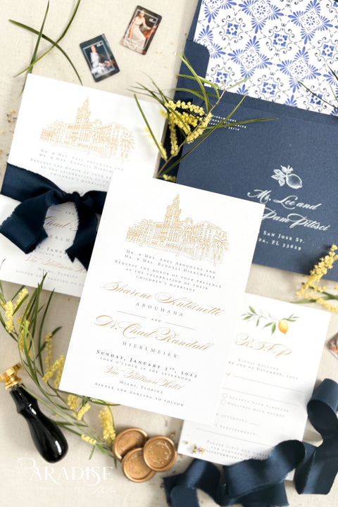 Inspired by the golden light and charm of European summers, this wedding invitation suite combines custom hand-drawn architecture with delicate watercolor lemons for a design that’s both luxurious and full of life. The venue illustration is created by hand, transforming your wedding location into a piece of art that sets the tone for your day. Paired with rich navy envelopes, an ornate blue patterned liner, and velvet ribbon accents, the result is a suite that exudes elegance and personality.