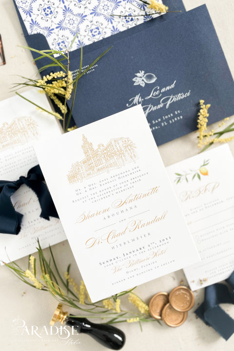 Inspired by the golden light and charm of European summers, this wedding invitation suite combines custom hand-drawn architecture with delicate watercolor lemons for a design that’s both luxurious and full of life. The venue illustration is created by hand, transforming your wedding location into a piece of art that sets the tone for your day. Paired with rich navy envelopes, an ornate blue patterned liner, and velvet ribbon accents, the result is a suite that exudes elegance and personality.