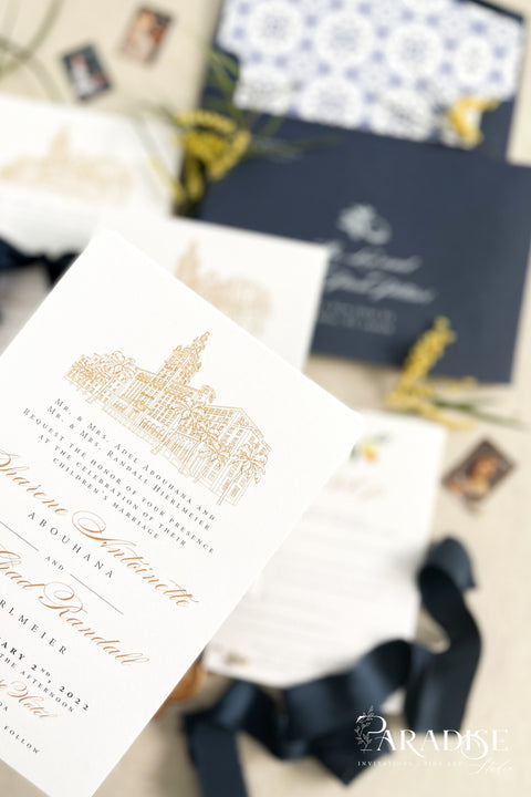 Inspired by the golden light and charm of European summers, this wedding invitation suite combines custom hand-drawn architecture with delicate watercolor lemons for a design that’s both luxurious and full of life. The venue illustration is created by hand, transforming your wedding location into a piece of art that sets the tone for your day. Paired with rich navy envelopes, an ornate blue patterned liner, and velvet ribbon accents, the result is a suite that exudes elegance and personality.