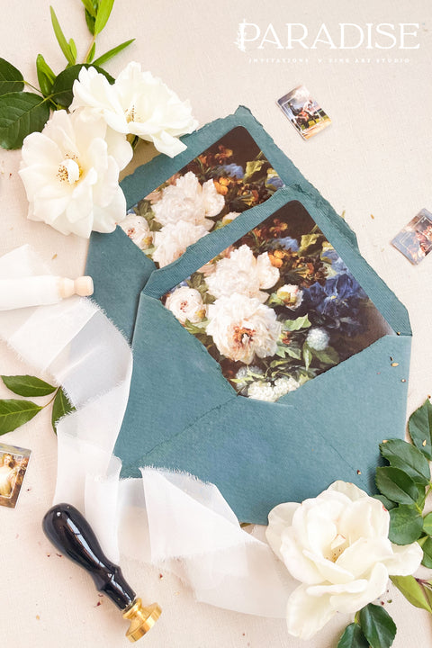 Emerald wedding envelopes with floral envelope liners, styled flat lay with white florals, greenery, and wax seals, perfect for romantic and botanical invitation suites.