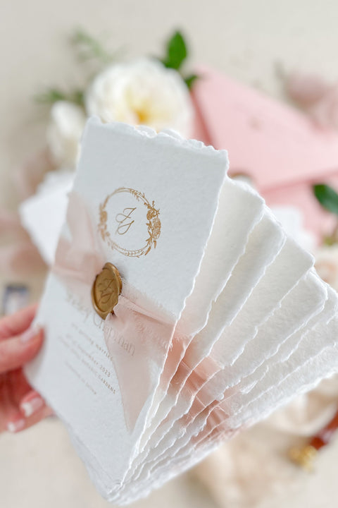 Announce your wedding with elegance and artistry through our handmade paper Save the Date cards, featuring a gold monogram wreath, soft blush silk ribbon, and hand-stamped wax seal. Each card is crafted on luxury 100% cotton handmade paper with deckled edges, offering a tactile and romantic texture that perfectly captures fine-art wedding style.