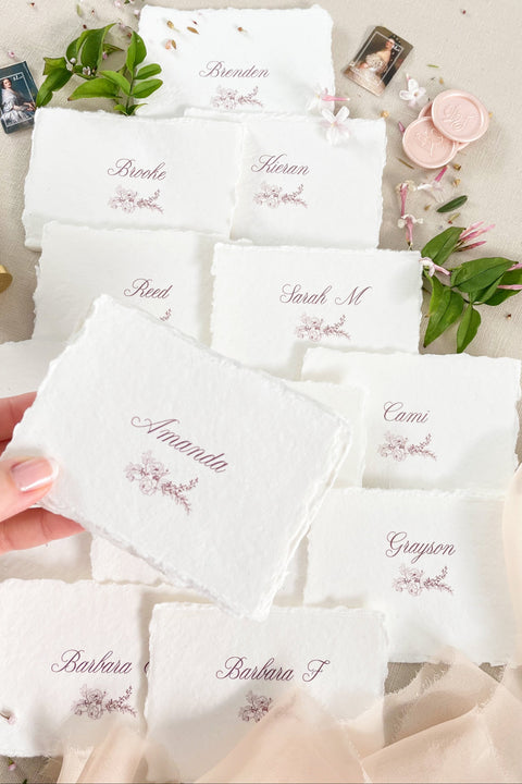 Bring soft elegance to your tablescape with our handmade paper place cards, crafted from luxurious cotton rag paper and finished with naturally torn deckled edges. Each card features romantic calligraphy paired with a delicate floral illustration, creating a fine-art aesthetic perfect for weddings, showers, intimate dinners, and elevated celebrations. These artisan-crafted pieces add organic texture, timeless beauty, and refined charm to any event setting.