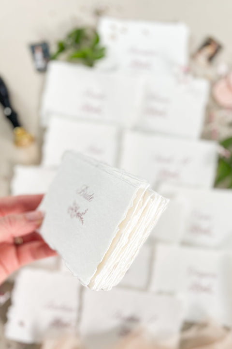 Bring soft elegance to your tablescape with our handmade paper place cards, crafted from luxurious cotton rag paper and finished with naturally torn deckled edges. Each card features romantic calligraphy paired with a delicate floral illustration, creating a fine-art aesthetic perfect for weddings, showers, intimate dinners, and elevated celebrations. These artisan-crafted pieces add organic texture, timeless beauty, and refined charm to any event setting.