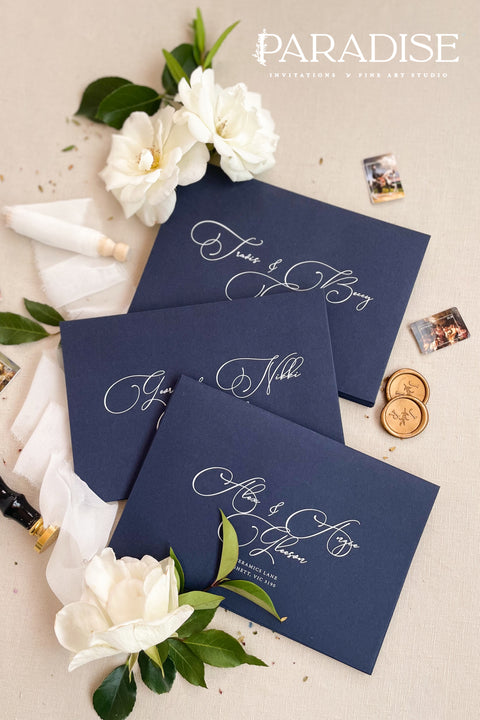 Navy wedding envelopes with white ink address printing, styled flat lay with ivory florals, wax seals, and greenery, perfect for classic and elegant invitation suites.