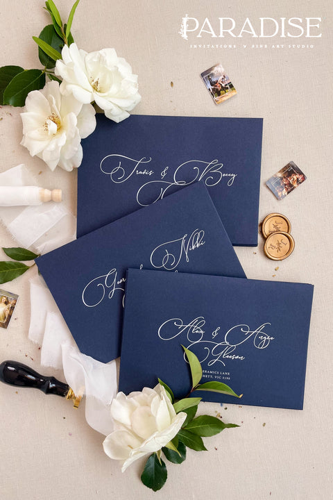Navy wedding envelopes with white ink address printing, styled flat lay with ivory florals, wax seals, and greenery, perfect for classic and elegant invitation suites.