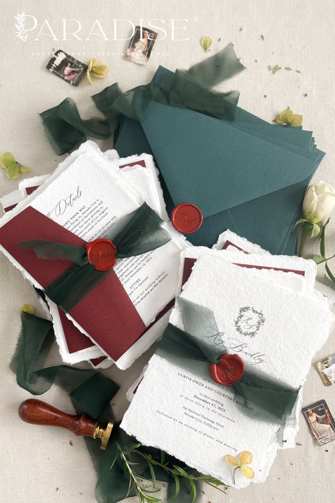 This handmade wedding invitation suite captures the essence of fine art stationery with a touch of deep, moody charm. Printed on luxury cotton paper with natural deckled edges. The suite is adorned with your custom monogram - hand-drawn to reflect your initials and personal style - and wrapped in a forest green silk ribbon with a red wax seal for a dramatic yet refined finish. Paired with rich burgundy backing cards and green envelopes.