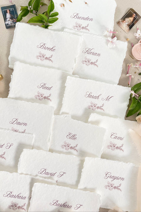 Bring soft elegance to your tablescape with our handmade paper place cards, crafted from luxurious cotton rag paper and finished with naturally torn deckled edges. Each card features romantic calligraphy paired with a delicate floral illustration, creating a fine-art aesthetic perfect for weddings, showers, intimate dinners, and elevated celebrations. These artisan-crafted pieces add organic texture, timeless beauty, and refined charm to any event setting.