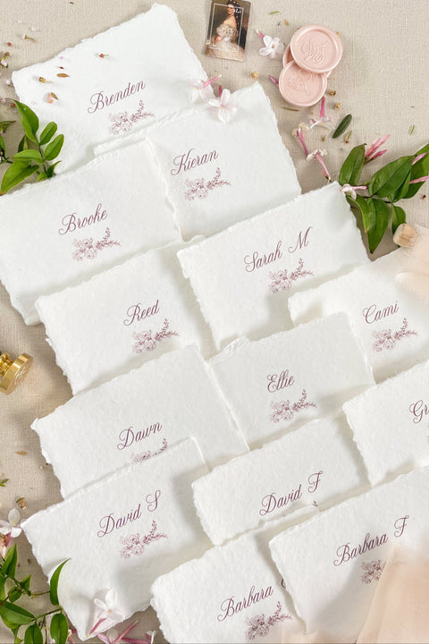 Bring soft elegance to your tablescape with our handmade paper place cards, crafted from luxurious cotton rag paper and finished with naturally torn deckled edges. Each card features romantic calligraphy paired with a delicate floral illustration, creating a fine-art aesthetic perfect for weddings, showers, intimate dinners, and elevated celebrations. These artisan-crafted pieces add organic texture, timeless beauty, and refined charm to any event setting.