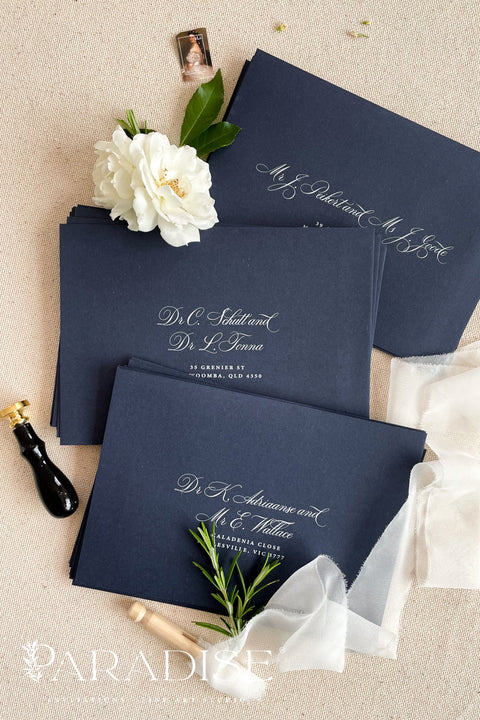Navy wedding envelopes with white ink address printing, styled flat lay with ivory florals, wax seals, and greenery, perfect for classic and elegant invitation suites.