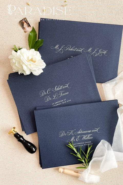 Navy wedding envelopes with white ink address printing, styled flat lay with ivory florals, wax seals, and greenery, perfect for classic and elegant invitation suites.