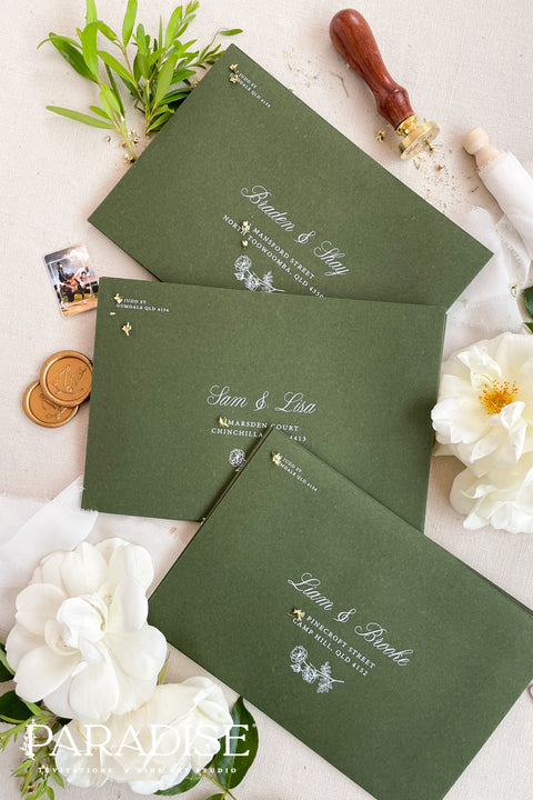 Forest green wedding envelopes with printed addresses, styled flat lay with white florals, wax seals, and greenery, perfect for botanical and elegant invitation suites.