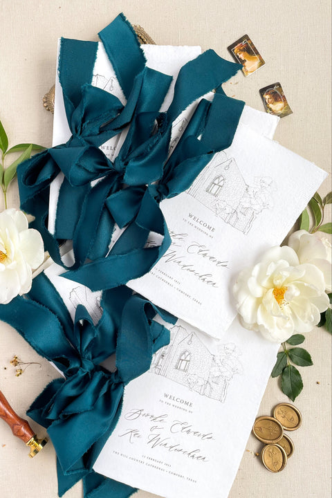 Hand-drawn venue artwork meets fine-art craftsmanship in these beautifully assembled wedding programs. The soft blue ribbon, textured cotton paper, and delicate illustration create an heirloom-quality piece that sets the tone for a romantic, detail-rich ceremony. Each program balances sophistication with warmth, offering guests a meaningful preview of your celebration.