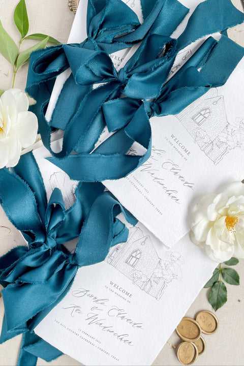 Hand-drawn venue artwork meets fine-art craftsmanship in these beautifully assembled wedding programs. The soft blue ribbon, textured cotton paper, and delicate illustration create an heirloom-quality piece that sets the tone for a romantic, detail-rich ceremony. Each program balances sophistication with warmth, offering guests a meaningful preview of your celebration.