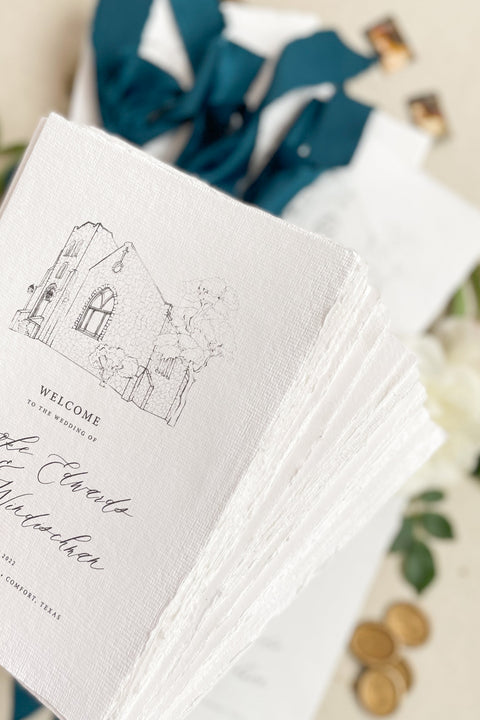 Hand-drawn venue artwork meets fine-art craftsmanship in these beautifully assembled wedding programs. The soft blue ribbon, textured cotton paper, and delicate illustration create an heirloom-quality piece that sets the tone for a romantic, detail-rich ceremony. Each program balances sophistication with warmth, offering guests a meaningful preview of your celebration.
