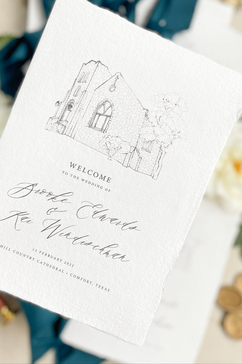 Hand-drawn venue artwork meets fine-art craftsmanship in these beautifully assembled wedding programs. The soft blue ribbon, textured cotton paper, and delicate illustration create an heirloom-quality piece that sets the tone for a romantic, detail-rich ceremony. Each program balances sophistication with warmth, offering guests a meaningful preview of your celebration.