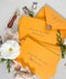 Amber wedding envelopes with printed addresses, styled flat lay with white florals, wax seal, ribbon, and greenery, perfect for warm, elegant invitation suites.
