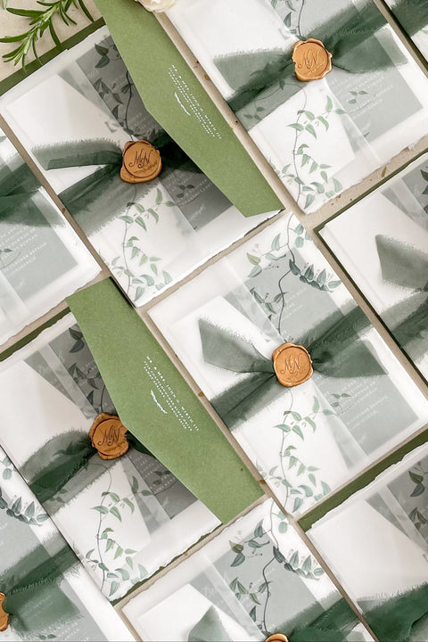 This handmade paper wedding invitation suite is designed for couples who cherish natural beauty and fine art craftsmanship. Each invitation is printed on luxury deckled-edge cotton paper, offering a rich, tactile texture that reflects the care and artistry poured into every detail. Encased in a botanical vellum jacket and hand-tied with a deep green silk ribbon and wax seal, this suite embodies organic elegance. It feels like a keepsake from nature itself - graceful, heartfelt, and timeless. 