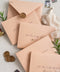 Soft beige envelopes featuring black ink calligraphy address printing, photographed with wax seals and styling props for elegant wedding stationery.