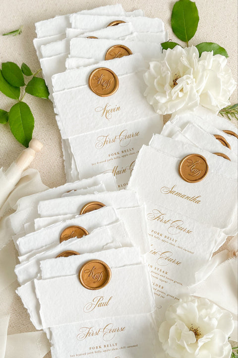 Refine your tablescape with our handmade paper wedding menus with personalized name tags, a luxurious detail that blends artistry and function. Each menu is printed on deckled-edge cotton paper and wrapped in a soft handmade band topped with a vintage gold wax seal - creating a timeless, cohesive aesthetic. Designed for elegant fine-art weddings, these menus double as place cards, adding personalization and charm to every seat.