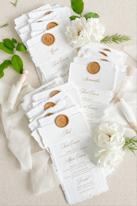 Refine your tablescape with our handmade paper wedding menus with personalized name tags, a luxurious detail that blends artistry and function. Each menu is printed on deckled-edge cotton paper and wrapped in a soft handmade band topped with a vintage gold wax seal - creating a timeless, cohesive aesthetic. Designed for elegant fine-art weddings, these menus double as place cards, adding personalization and charm to every seat.