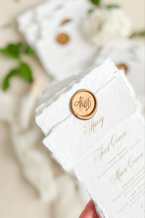 Refine your tablescape with our handmade paper wedding menus with personalized name tags, a luxurious detail that blends artistry and function. Each menu is printed on deckled-edge cotton paper and wrapped in a soft handmade band topped with a vintage gold wax seal - creating a timeless, cohesive aesthetic. Designed for elegant fine-art weddings, these menus double as place cards, adding personalization and charm to every seat.