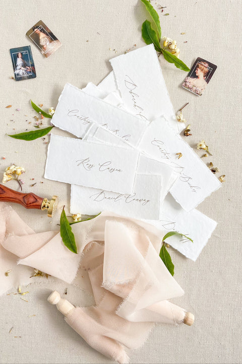 Create a timeless, romantic tablescape with our handmade paper place cards, crafted from luxurious cotton rag paper and finished with natural deckled edges. Each piece features elegant handwritten calligraphy and a soft fine-art texture that complements weddings, intimate dinners, bridal showers, and elevated celebrations. Their artisanal character and organic feel bring warmth, refinement, and delicate charm to any event setting.
