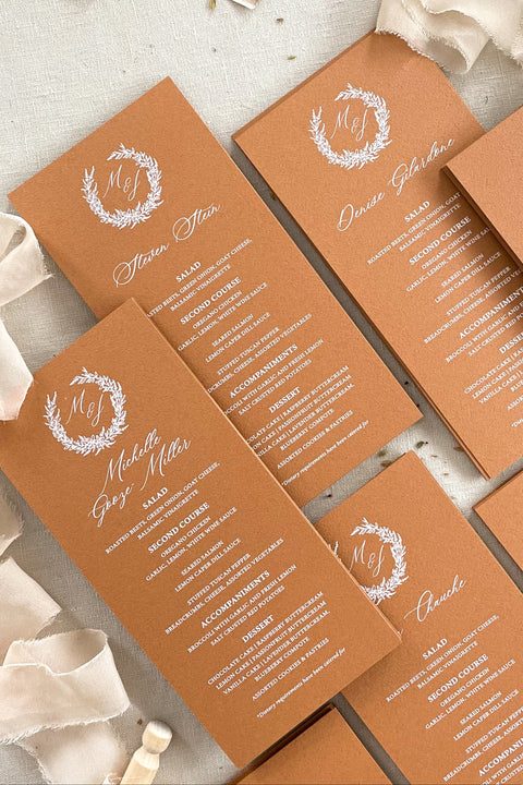 Bring a warm, refined touch to your tablescape with our terracotta wedding menus, designed for couples who love earthy elegance and fine-art craftsmanship. Each menu is printed on premium cardstock in a rich, burnt-clay hue that pairs beautifully with autumnal, bohemian, or rustic wedding palettes. The white wreath monogram adds a timeless detail that unites your stationery suite with your table décor.