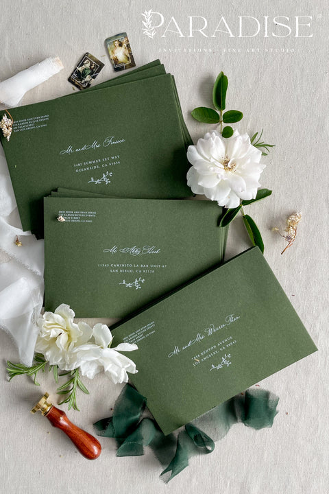 Elegant deep green wedding envelopes with white ink address printing, styled flat lay with wax seals and florals, perfect for modern and classic invitation suites.
