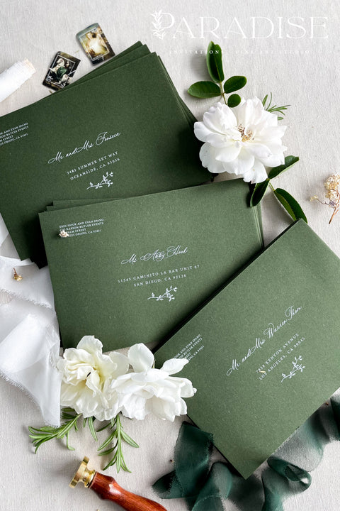 Elegant deep green wedding envelopes with white ink address printing, styled flat lay with wax seals and florals, perfect for modern and classic invitation suites.