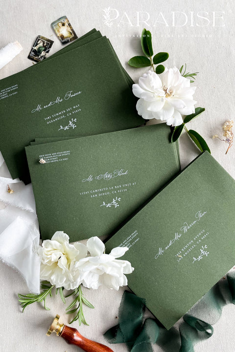 Elegant deep green wedding envelopes with white ink address printing, styled flat lay with wax seals and florals, perfect for modern and classic invitation suites.