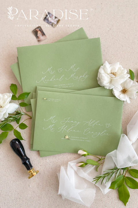 Stacked pear green wedding envelopes with printed addresses, styled with ribbon and floral accents for modern, nature-inspired stationery.
